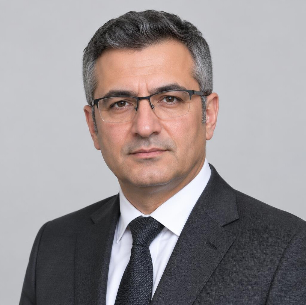 Studio portrait of a Turkish male economy editor in his 40s wearing glasses